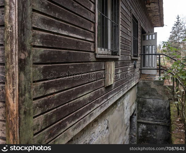 Brown weathered facade of an old abandoned wooden house in the mountains, close-up view from the house corner