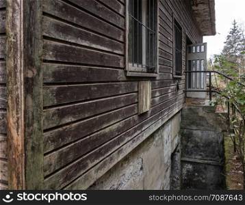 Brown weathered facade of an old abandoned wooden house in the mountains, close-up view from the house corner