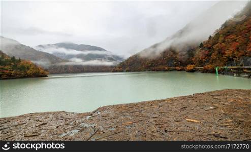 brown wood block floating in front of the dam and river mountain fog view background in autumn season Japan