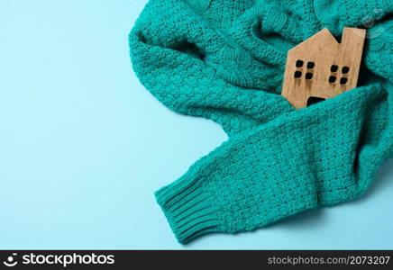 brown wooden model of the house is wrapped in a warm knitted sweater. Loan concept for house insulation, alternative energy