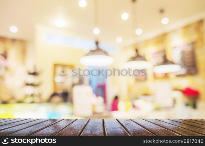 Brown wooden table over blurred photo of beautiful coffee shop for background use