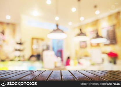 Brown wooden table over blurred photo of beautiful coffee shop for background use