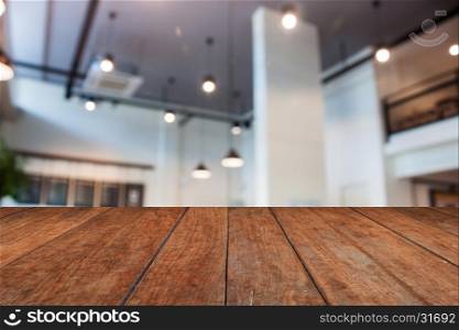 Brown wooden table top with abstract blur coffee shop interior for background