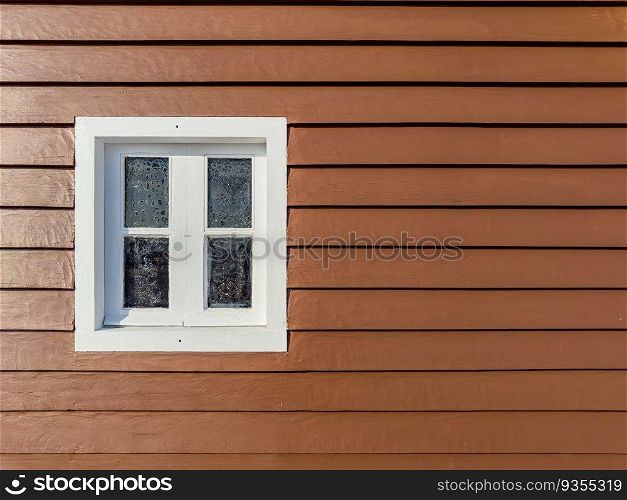 Brown wooden wall with white window. Close up.