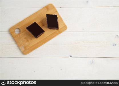 brownie cake on a bamboo tray on a white wooden background with space for textt. top view