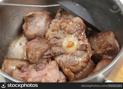 Browning oxtail in oil in a pan as a preparation for making a stew or a soup.