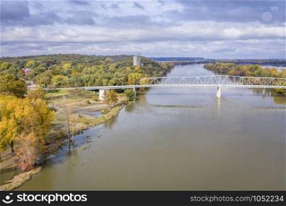 Brownville Bridge built in 1939 is a truss bridge over the Missouri River on U.S. Route 136 from Nemaha County, Nebraska, to Atchison County, Missouri, at Brownville, Nebraska, aerial view in fall scenery with high water flow.