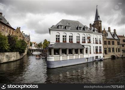 BRUGES, BELGIUM - SEPTEMBER 05, 2018: Canal in Bruges and famous Belfry tower on the background in a beautiful autumn day, Belgium on September 05, 2018