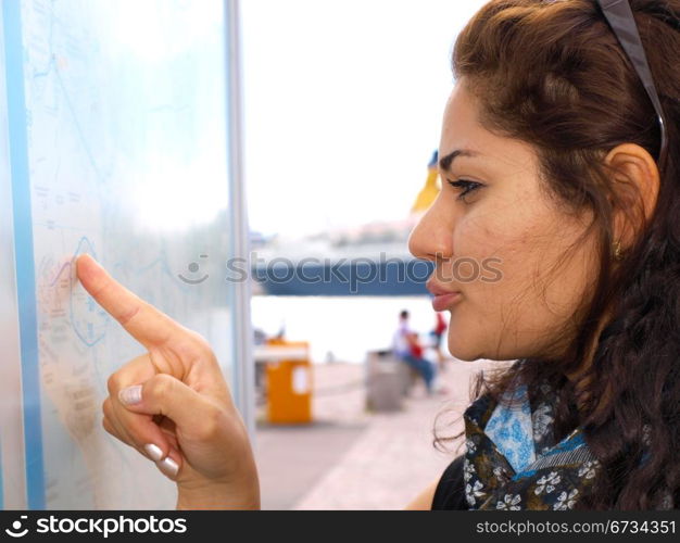 Brunet female smiling and pointing at a map
