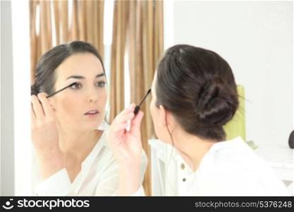 Brunette applying mascara in mirror