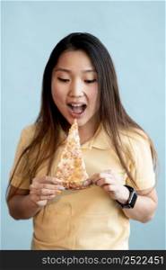 brunette asian woman eating slice pizza