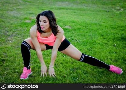Brunette athlete doing stretching exercise in nature.