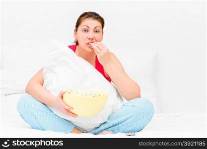 Brunette attentively watching television and eating popcorn