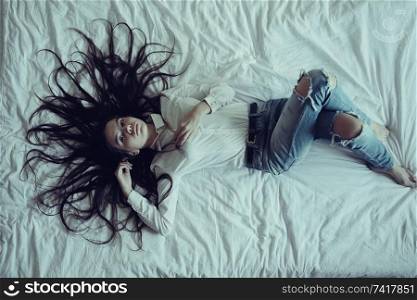 Brunette beautiful young adult with long hair lying on the bed