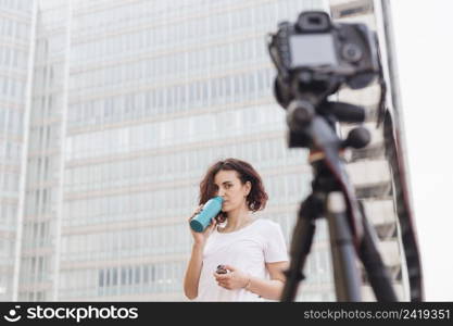 brunette blogger drinking water from bottle