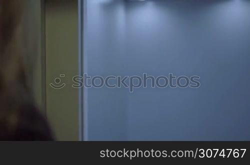 brunette business woman in elevator pressing button