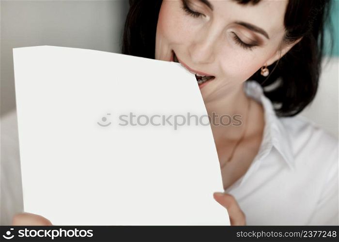 brunette businesswoman bites books moke up, reads or keeps. girl with dark short hair in a white shirt, studio isolated portrait emotions.. brunette businesswoman bites books moke up, reads or keeps. girl with dark short hair in a white shirt, studio isolated portrait emotions