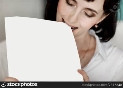 brunette businesswoman bites books moke up, reads or keeps. girl with dark short hair in a white shirt, studio isolated portrait emotions.. brunette businesswoman bites books moke up, reads or keeps. girl with dark short hair in a white shirt, studio isolated portrait emotions