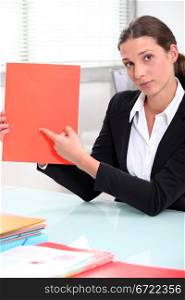 Brunette businesswoman pointing to a file left blank for your image