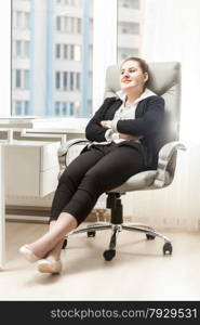 Brunette businesswoman relaxing in leather chair at office