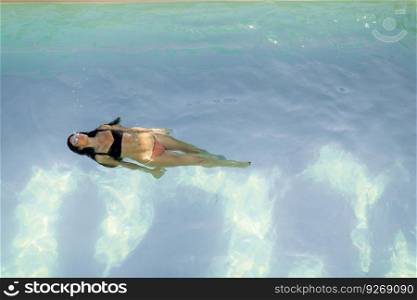 Brunette caucasian woman in  bikini floating in the pool water