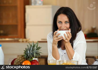 Brunette drinking from breakfast bowl