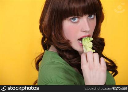 Brunette eating leaf of lettuce