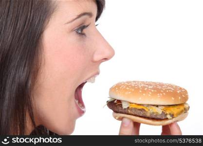 Brunette girl eating hamburger, profile-view