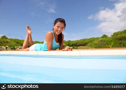 Brunette girl in fitness outfit relaxing by the pool