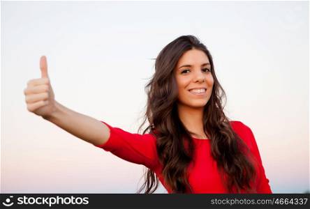 Brunette girl in red saying Ok with a white wall of background