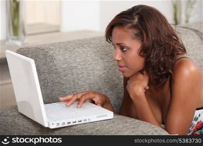 Brunette girl lying on couch with computer