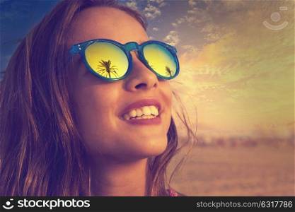 Brunette girl on beach sunglasses with palm tree reflection filtered image