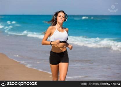 Brunette girl running on the beach with headphones