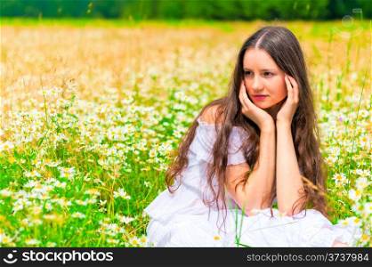 brunette girl sitting in camomiles