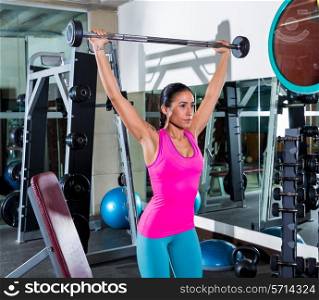 brunette girl wide grip barbell shoulder press workout at gym