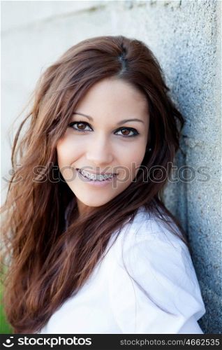 Brunette girl with brackets resting on a wall on the street