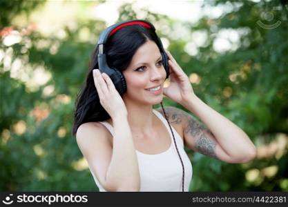 Brunette girl with headphones walking on a park