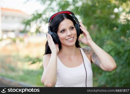 Brunette girl with headphones walking on a park