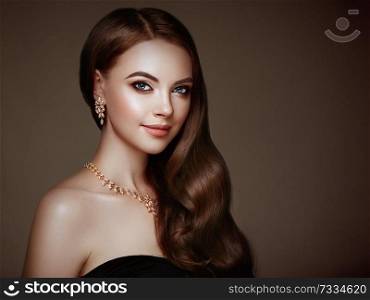 Brunette Girl with Long Healthy and Shiny Curly Hair. Care and Beauty. Beautiful Model Woman with Wavy Hairstyle. Make-Up and Jewelry