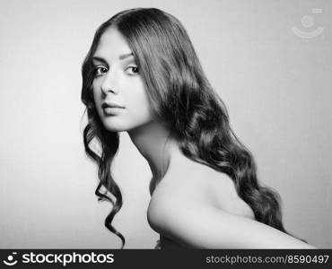 Brunette Girl with Long Healthy and Shiny Curly Hair. Care and Beauty. Beautiful Model Woman with Wavy Hairstyle. Black and White photo