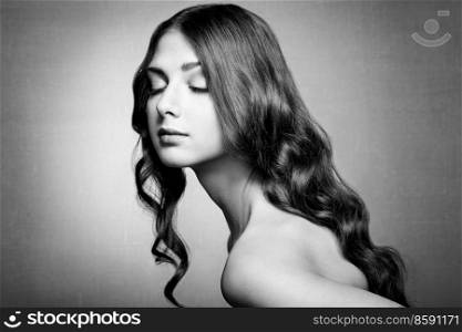 Brunette Girl with Long Healthy and Shiny Curly Hair. Care and Beauty. Beautiful Model Woman with Wavy Hairstyle. Black and White photo