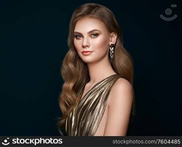 Brunette girl with perfect makeup. Beautiful model woman with curly hairstyle. Care and beauty hair products. Lady with fashionable gold makeup. Model with jewelry on dark background