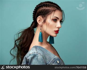 Brunette girl with perfect makeup. Beautiful model woman with curly hairstyle. Care and beauty hair products. Lady with braided hair. Model with jewelry. Turquoise background