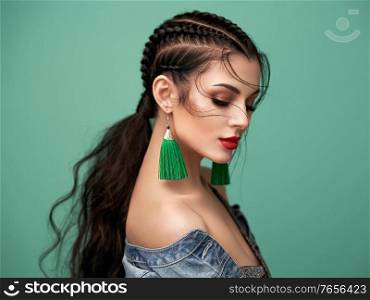 Brunette girl with perfect makeup. Beautiful model woman with curly hairstyle. Care and beauty hair products. Lady with braided hair. Model with jewelry. Turquoise background