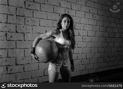 Brunette gym girl holding weighted ball relaxed