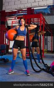 Brunette gym woman with weighted ball and rope posing