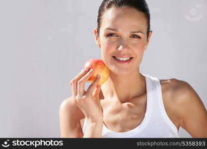 Brunette holding red apple to face