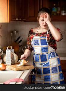Brunette housewife crying while cutting onion