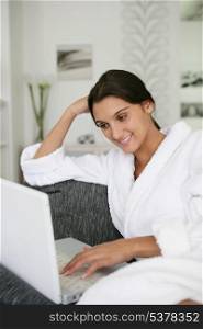 Brunette in bathing robe using laptop computer