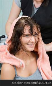 brunette in salon hair getting her hair dryied with a towel
